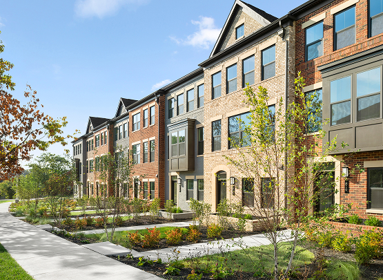 Row of modern multi-story Heartland Homes townhomes with red and beige brick facades
