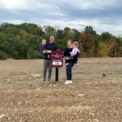 Family of four celebrating new home purchase at Heartland Homes lot