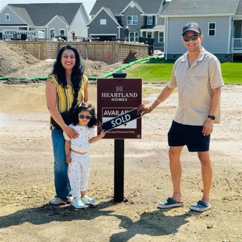 Family of three celebrating new home purchase at Heartland Homes construction site