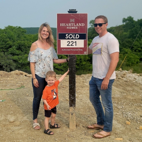 Family of three celebrating new home purchase at Heartland Homes lot